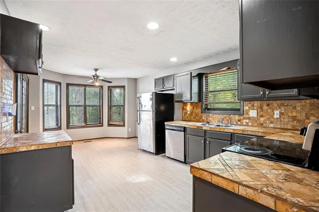 a large kitchen with kitchen island a large counter top space a sink stainless steel appliances and cabinets