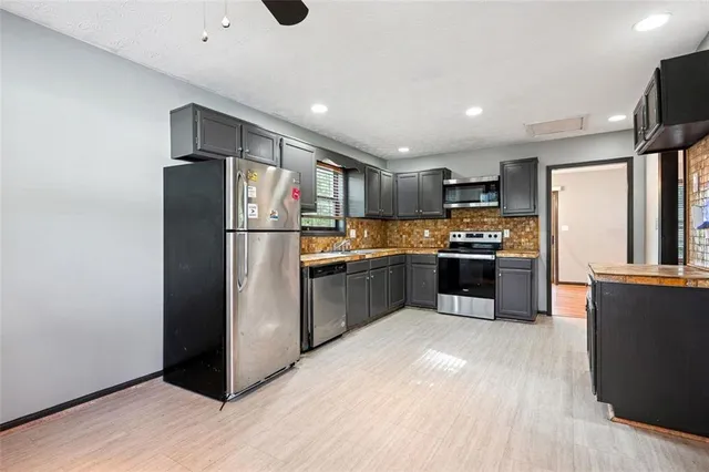 a kitchen with granite countertop stainless steel appliances a refrigerator cabinets and wooden floor