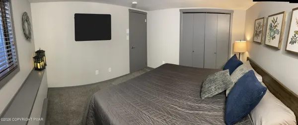 a bedroom with a bed and a flat tv screen on a dresser
