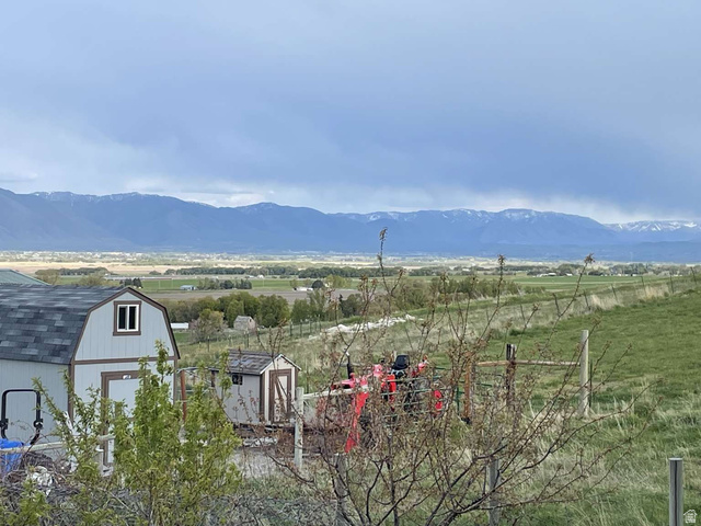 7030 West 2100 North Mendon, UT 84325 - Photo 14 of 67 Barn-style outbuilding with a shingle roof and a single window, set against a backdrop of distant mountains