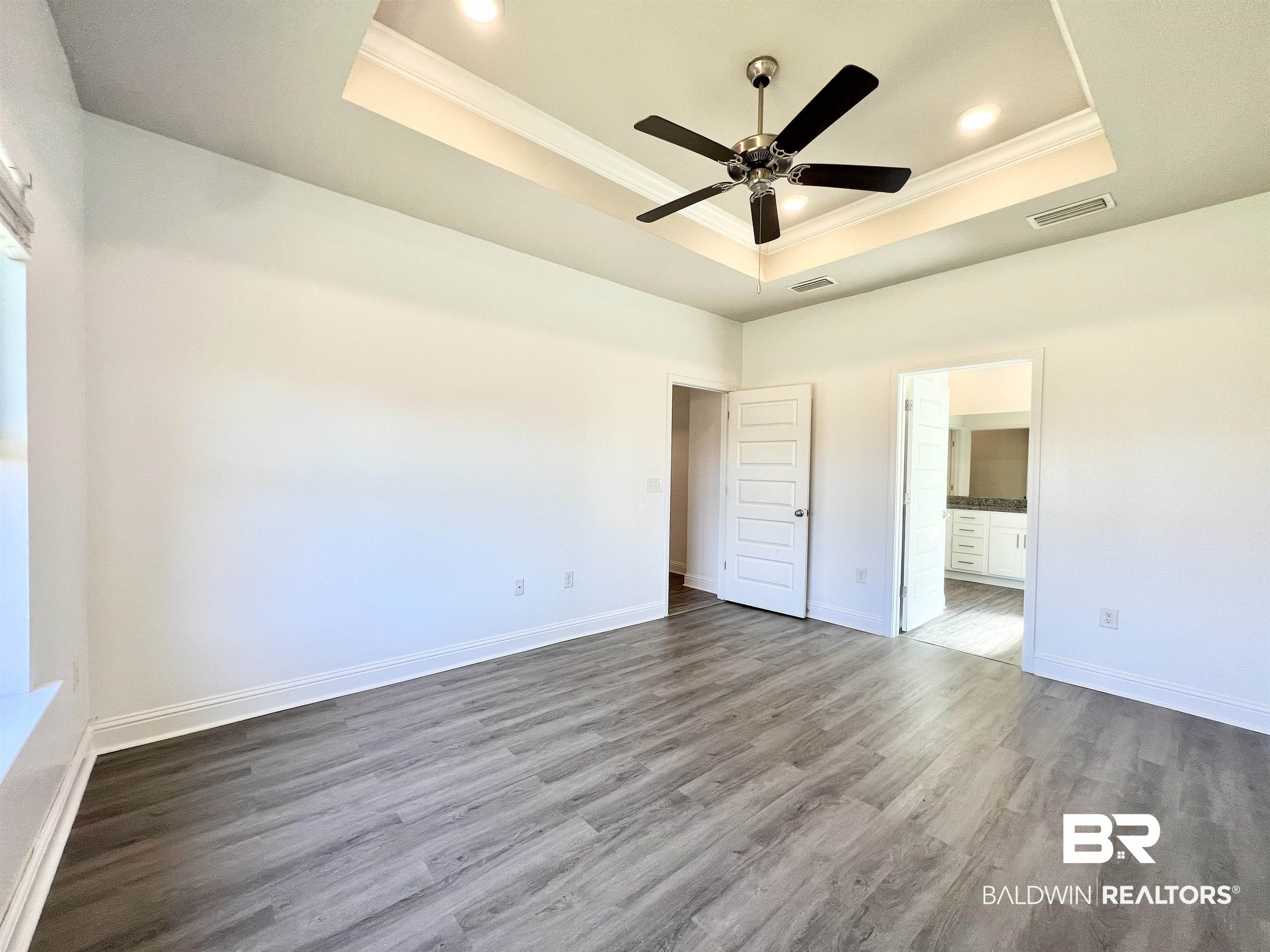 24785 Slater Mill Road Daphne, AL 36526 - Photo 25 of 46 Unfurnished bedroom featuring ensuite bathroom, wood-type flooring, a tray ceiling, ceiling fan, and crown molding
