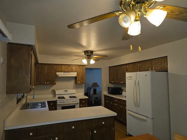 a kitchen with stainless steel appliances a sink a refrigerator center island and cabinets