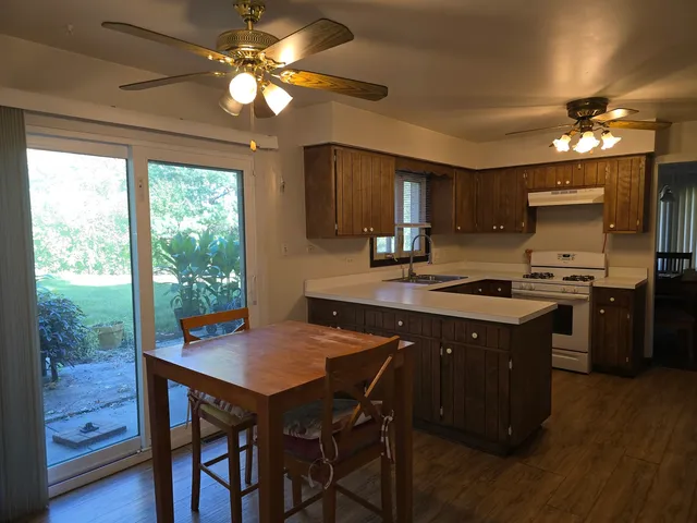 a kitchen with a stove a sink dishwasher a dining table and chairs with wooden floor