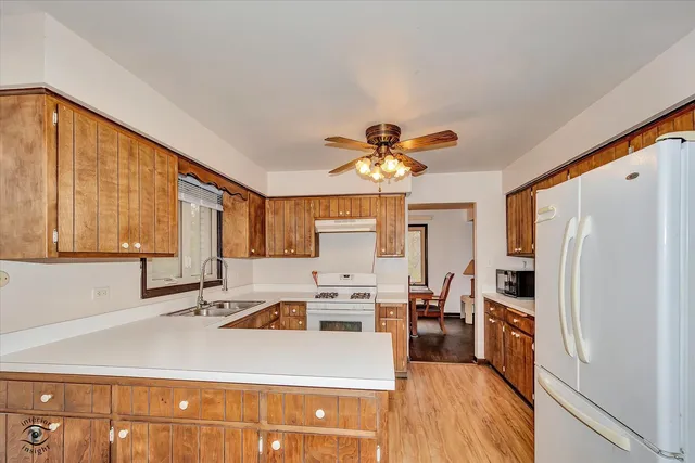 a kitchen with a refrigerator a sink and dishwasher with wooden floor