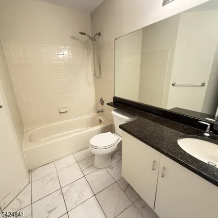 a bathroom with a granite countertop sink toilet a mirror and shower