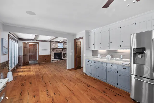 a kitchen with granite countertop a refrigerator oven a sink dishwasher and white cabinets with wooden floor