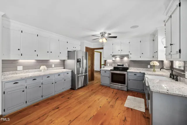 a kitchen with stainless steel appliances granite countertop a sink cabinets and wooden floor