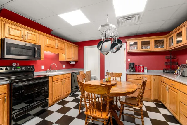 a kitchen with stainless steel appliances granite countertop a sink a stove and a dining table