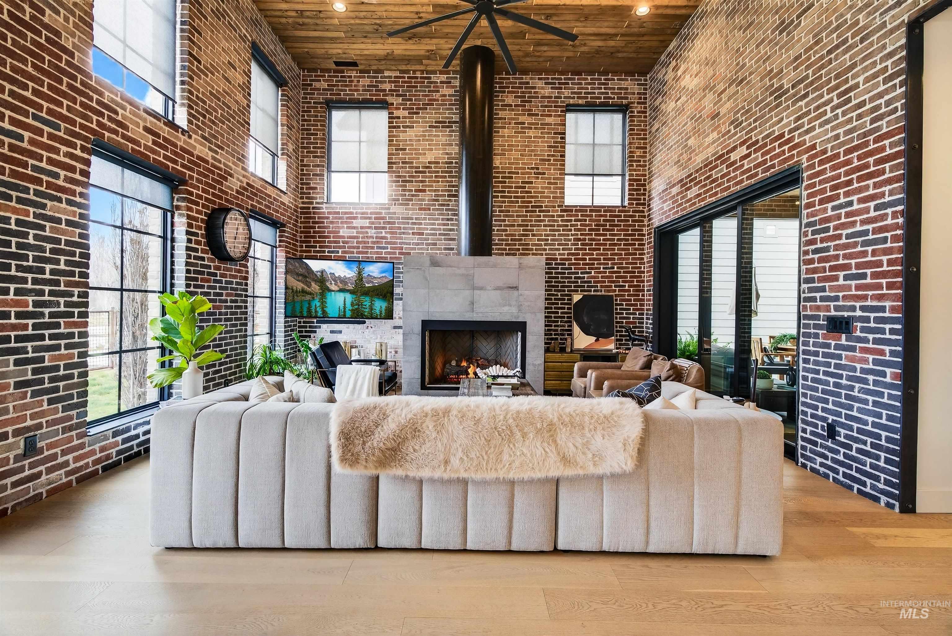 2526 West Rustic Forge Street Eagle, ID 83616 - Photo 22 of 50 Living area featuring a high ceiling, brick wall, wood finished floors, a tiled fireplace, and recessed lighting