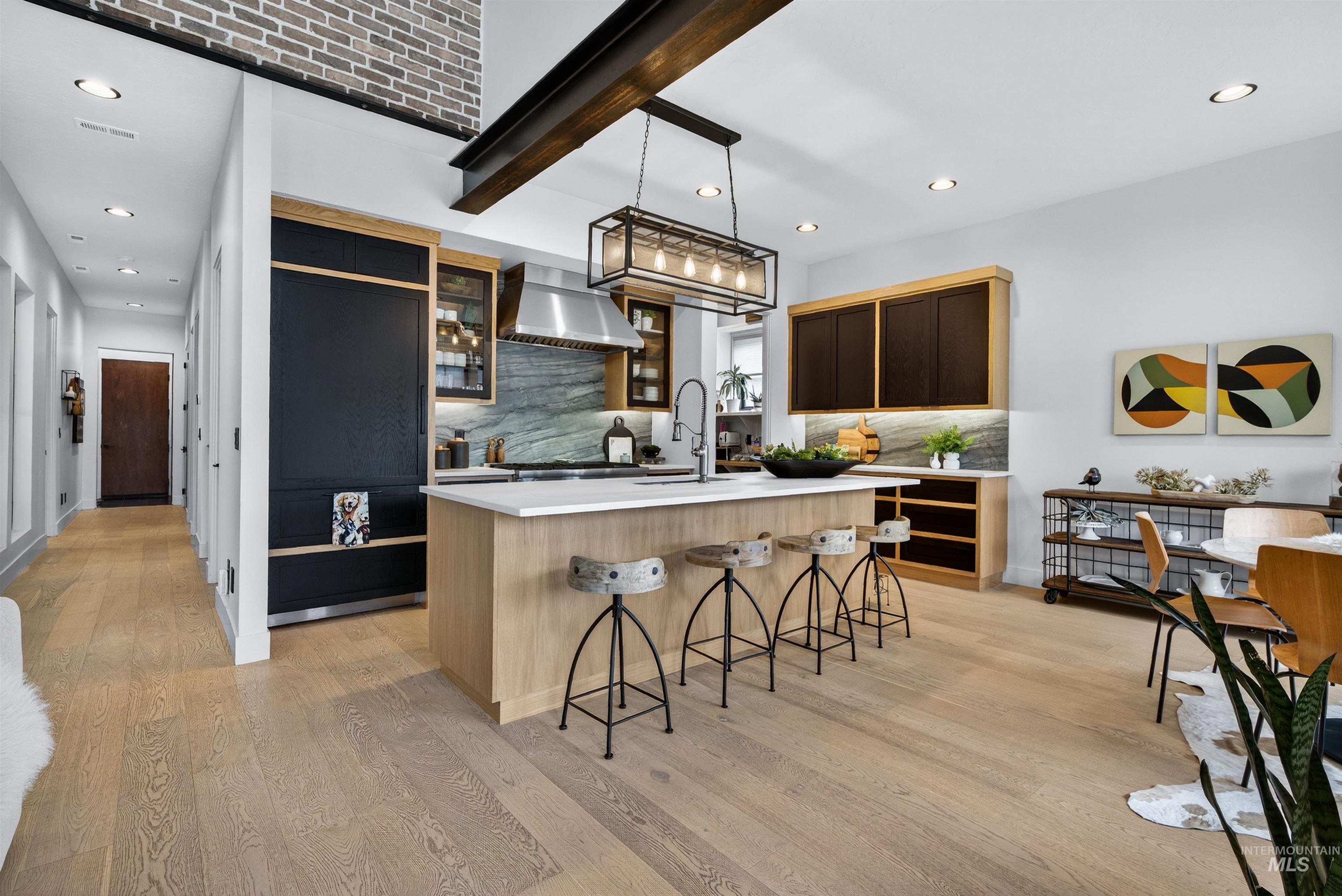 2526 West Rustic Forge Street Eagle, ID 83616 - Photo 23 of 50 Two tone kitchen featuring beam ceiling, a breakfast bar area, a center island with sink, decorative light fixtures, and glass insert cabinets