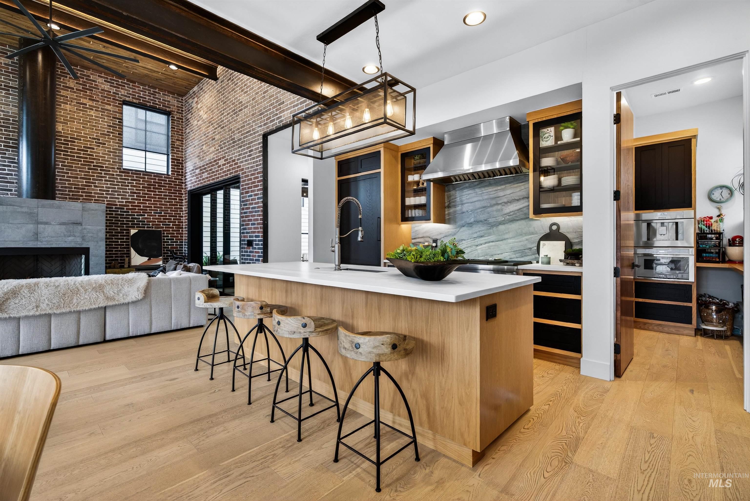 2526 West Rustic Forge Street Eagle, ID 83616 - Photo 25 of 50 Kitchen with brick wall, a breakfast bar, decorative light fixtures, a high ceiling, and a center island with sink