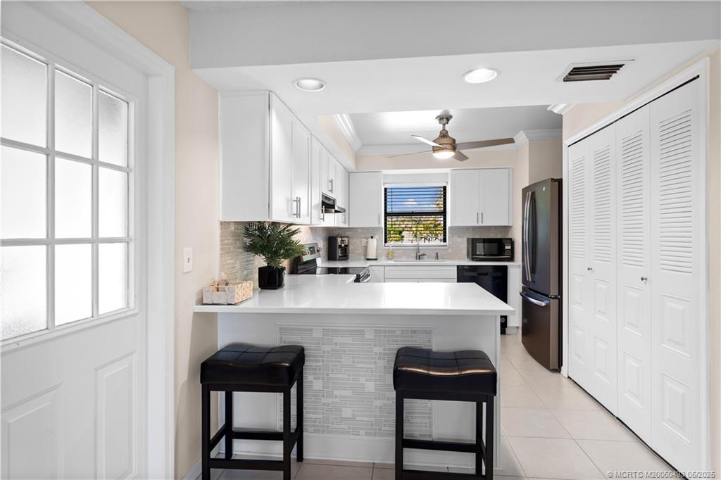 4885 Southeast Capstan Avenue, Unit E27 Stuart, FL 34997 - Photo 6 of 40 a kitchen with kitchen island a counter top space appliances and cabinets