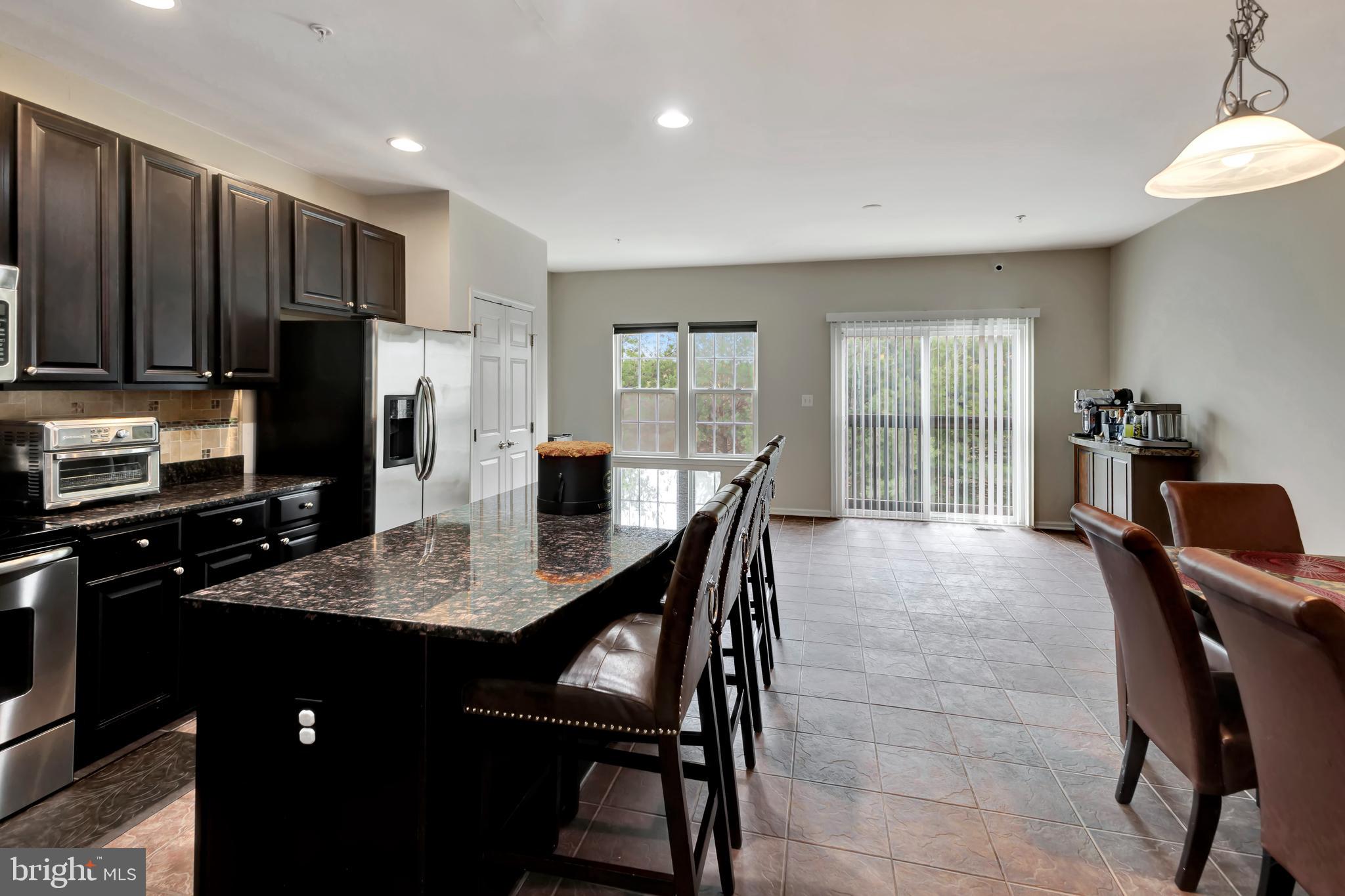 2063 Spring Run Circle Frederick, MD 21702 - Photo 14 of 28 a kitchen with stainless steel appliances granite countertop a stove a refrigerator a sink a dining table and chairs