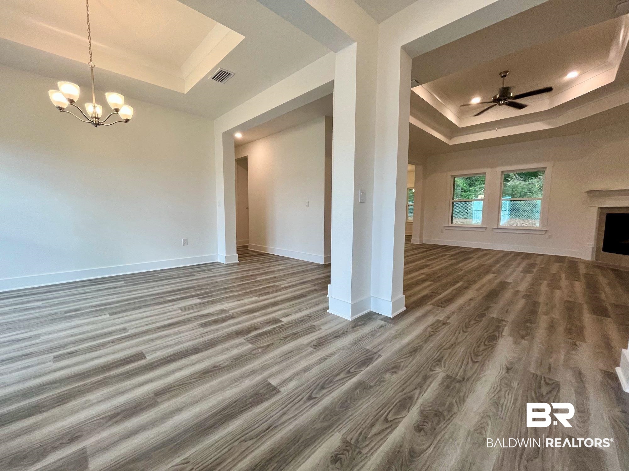 334 Barndling Street Fairhope, AL 36532 - Photo 7 of 34 Unfurnished living room with ceiling fan with notable chandelier, hardwood / wood-style flooring, and a tray ceiling