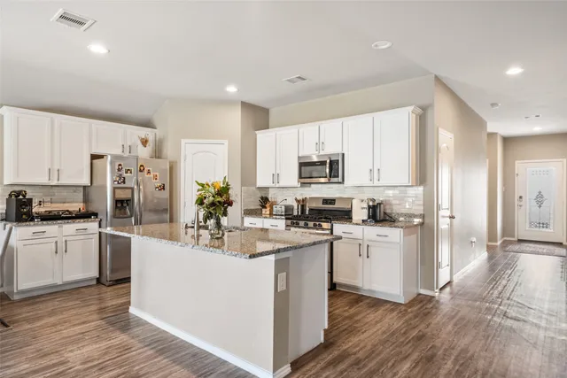 a kitchen with white cabinets and stainless steel appliances