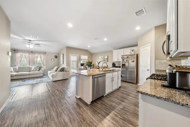 a large white kitchen with lots of counter space a sink and stainless steel appliances
