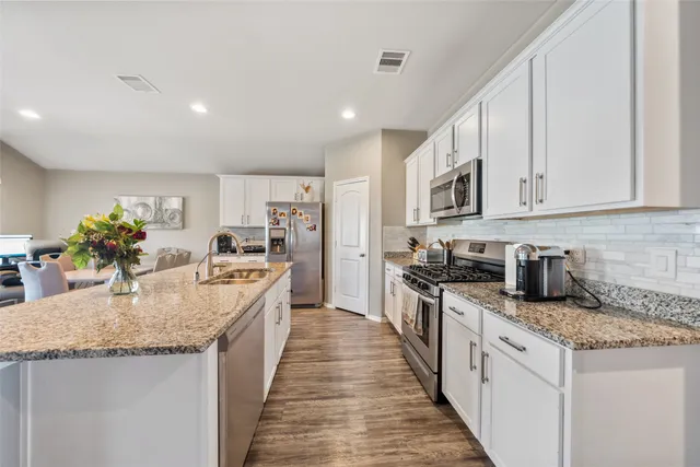 a kitchen with stainless steel appliances granite countertop lots of counter top space and wooden floor
