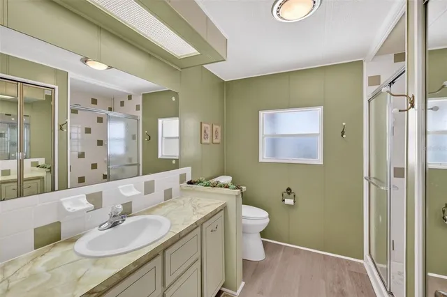 a bathroom with a granite countertop sink a toilet a mirror and shower