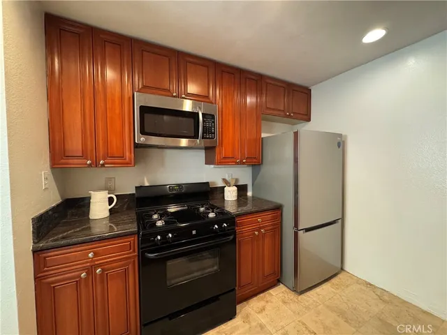 a kitchen with stainless steel appliances granite countertop a stove a refrigerator and a microwave