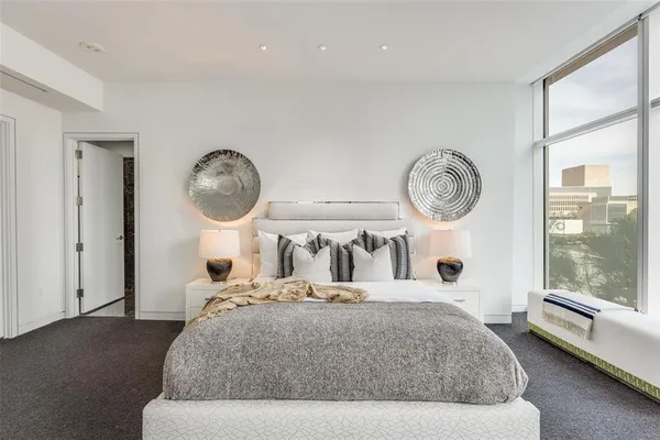 a bedroom with a bed a mirror and a large window