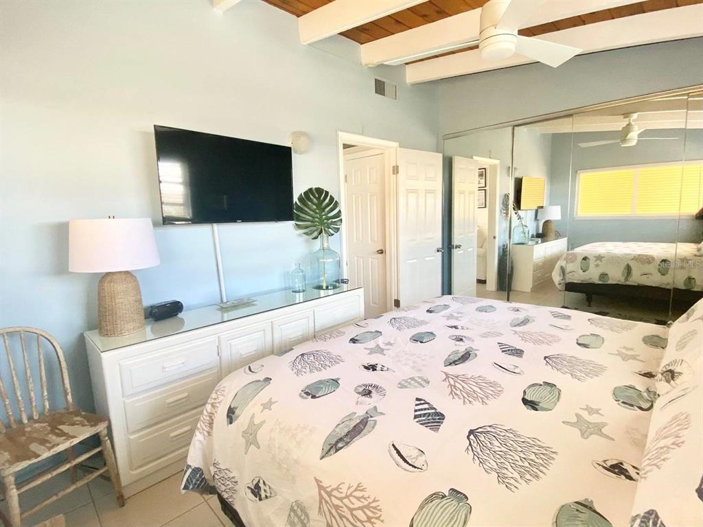 6006 Midnight Pass Road, Unit 71 Sarasota, FL 34242 - Photo 9 of 21 a bedroom with a large bed and a flat screen tv