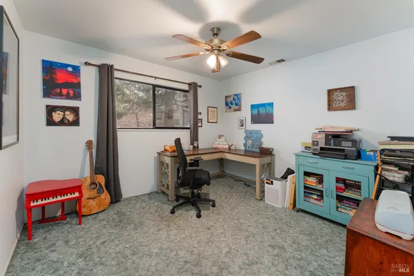 a view of a workspace with furniture and a fan