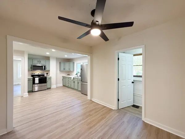 a view of a kitchen with wooden floor a sink and a refrigerator
