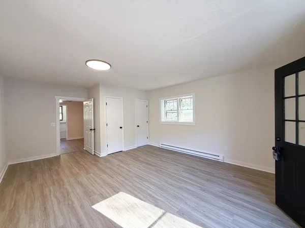 an empty room with windows and chandelier fan