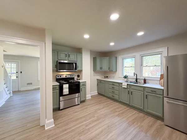 a large kitchen with stainless steel appliances granite countertop a stove and a sink