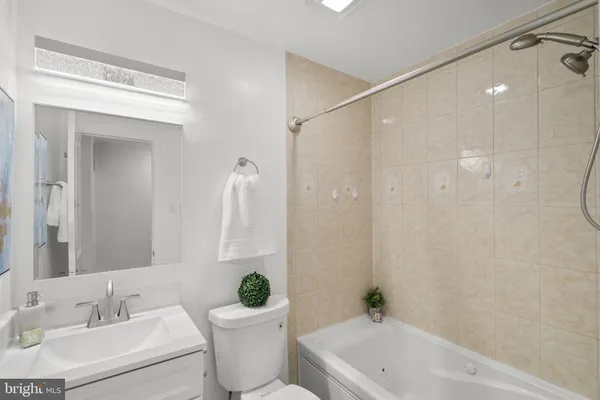 a bathroom with a bathtub shower sink vanity mirror and toilet