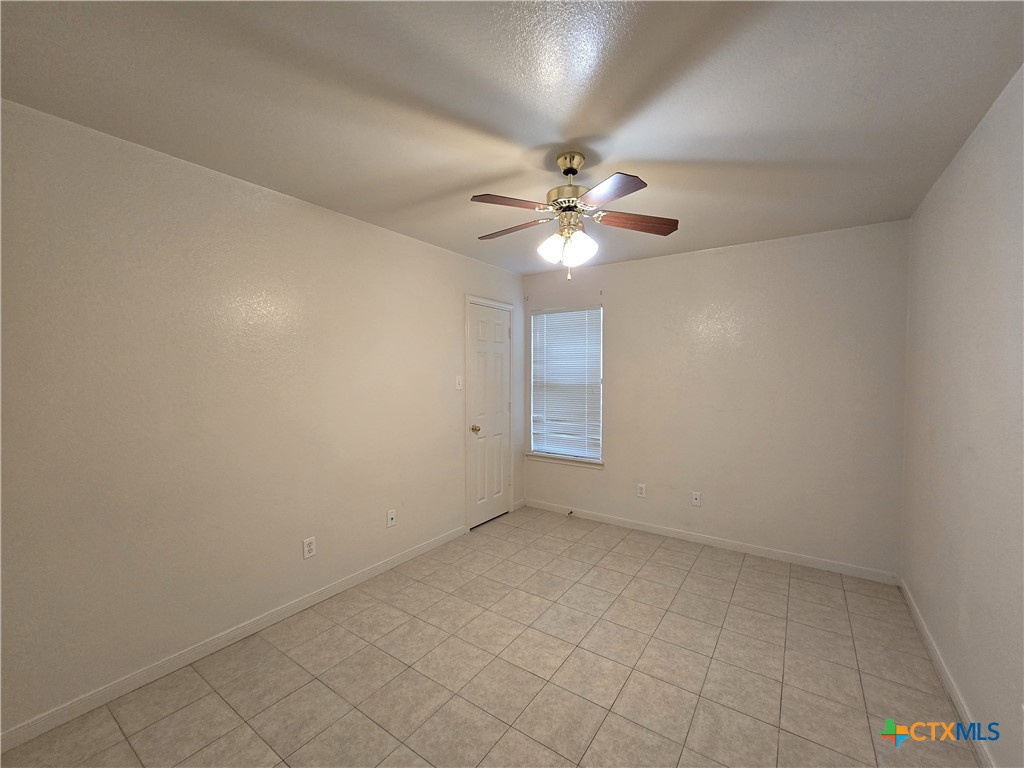 1411 Nicholas Circle, Unit B Killeen, TX 76542 - Photo 21 of 23 an empty room with a chandelier fan and windows