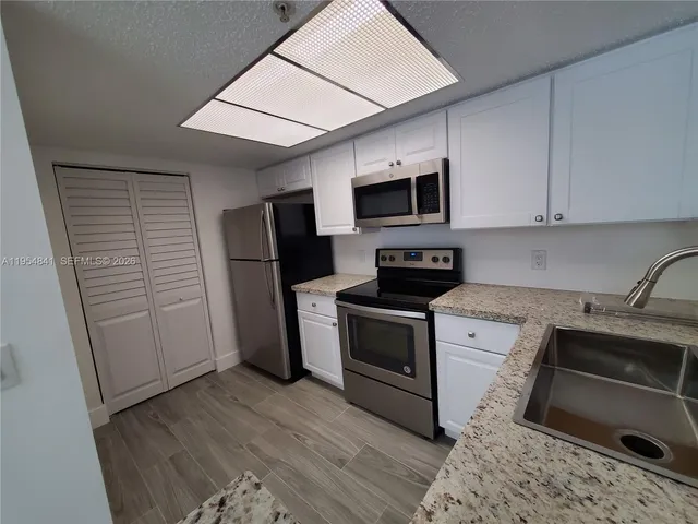 a kitchen with stainless steel appliances granite countertop a stove microwave and refrigerator