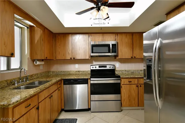 a kitchen with stainless steel appliances granite countertop a refrigerator a stove and a sink with wooden floor