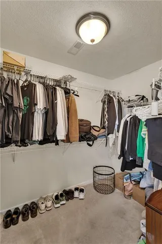 a view of walk in closet with clothes and shoes
