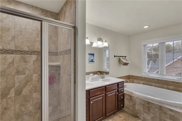 a bathroom with a tub sink vanity granite and shower