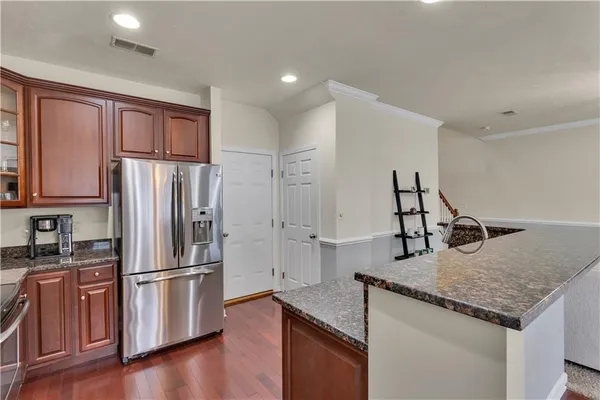 a kitchen with granite countertop a refrigerator and wooden cabinets