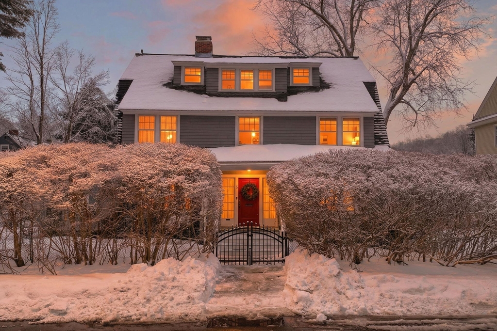 a front view of a house with large trees