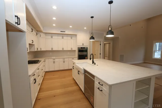 a large kitchen with kitchen island a stove a sink a refrigerator and a wooden floor