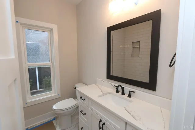 a bathroom with a granite countertop sink toilet and mirror