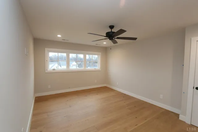 an empty room with windows and fan