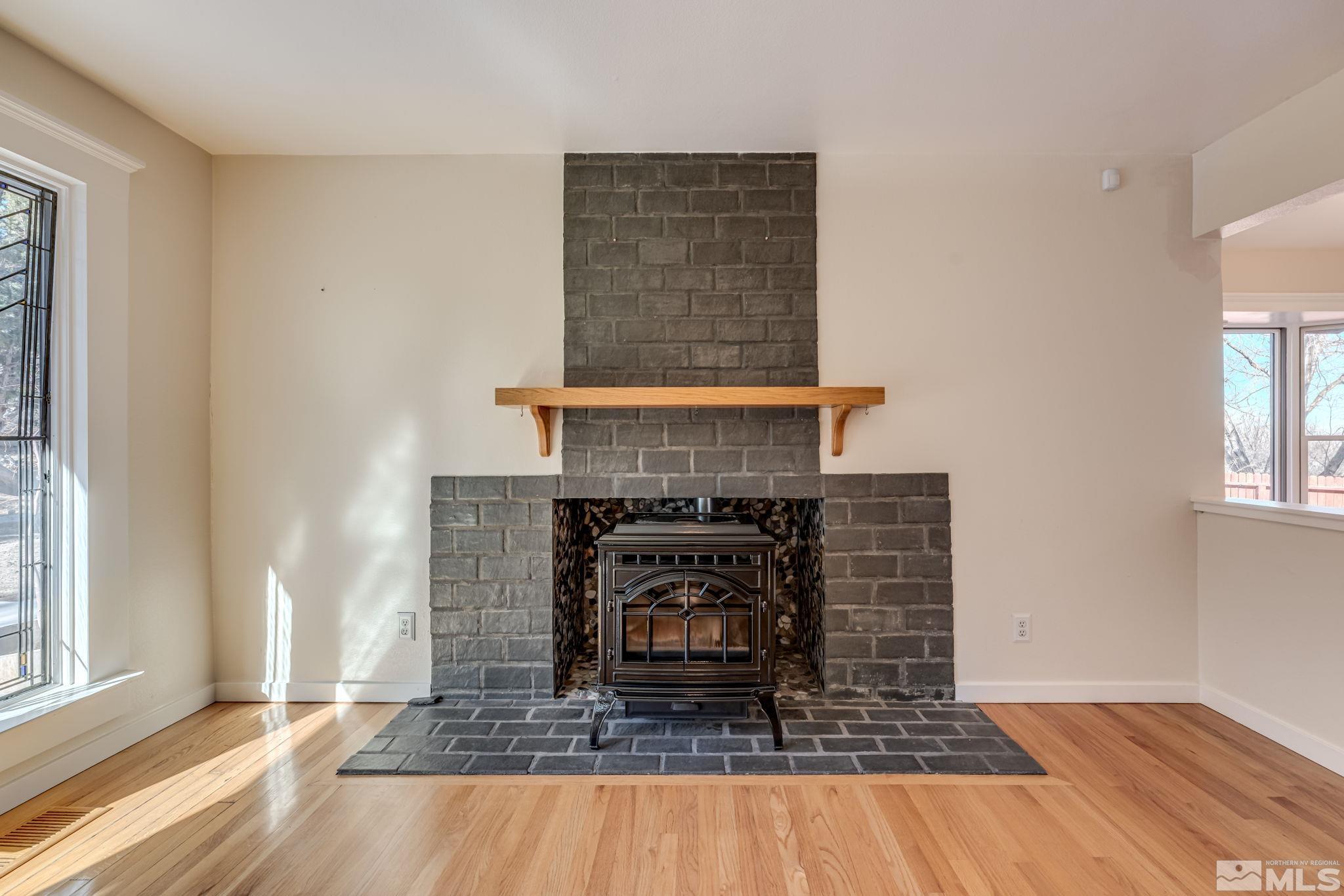 14185 Minnetonka Circle Reno, NV 89521 - Photo 13 of 32 an empty room with wooden floor a fireplace and windows