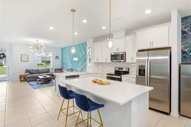 a kitchen with kitchen island a stove a sink a oven a refrigerator and chairs