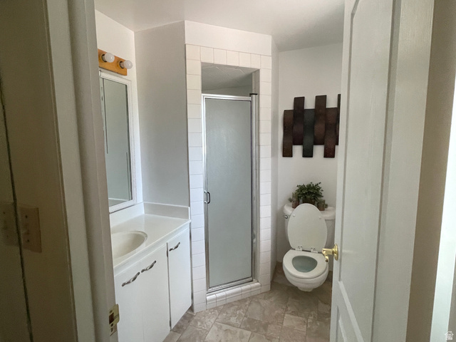 438 East Main Street Elsinore, UT 84724 - Photo 28 of 43 Full bathroom featuring a white vanity with integrated sink, a mirrored medicine cabinet, a corner shower with a glass enclosure, and a commode