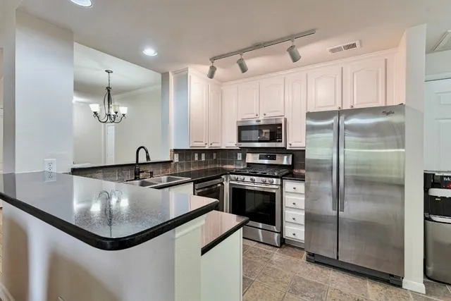 a kitchen with kitchen island granite countertop a sink stainless steel appliances and cabinets