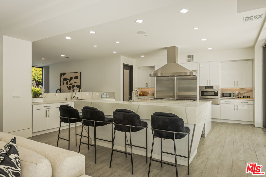 4230 Valley Meadow Road Encino, CA 91436 - Photo 14 of 44 a kitchen with stainless steel appliances a dining table chairs and sink