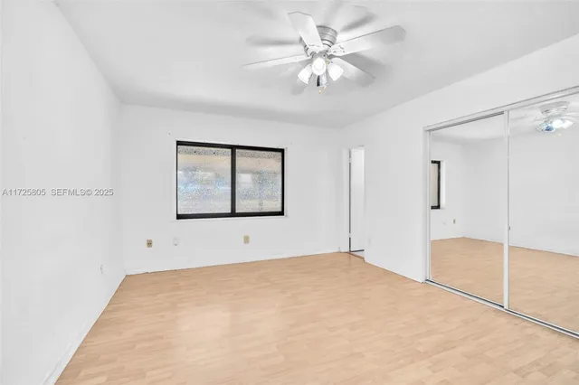 a view of an empty room with chandelier fan