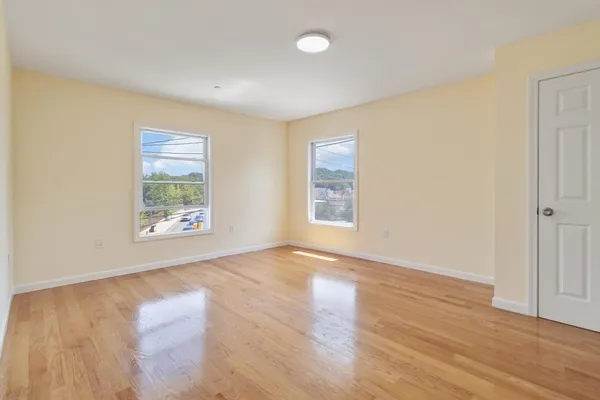 an empty room with wooden floor and windows