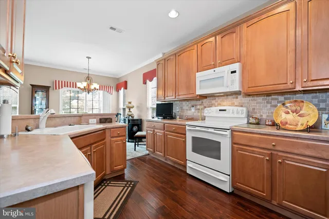a kitchen with stainless steel appliances granite countertop a stove a sink dishwasher and a refrigerator with wooden floor