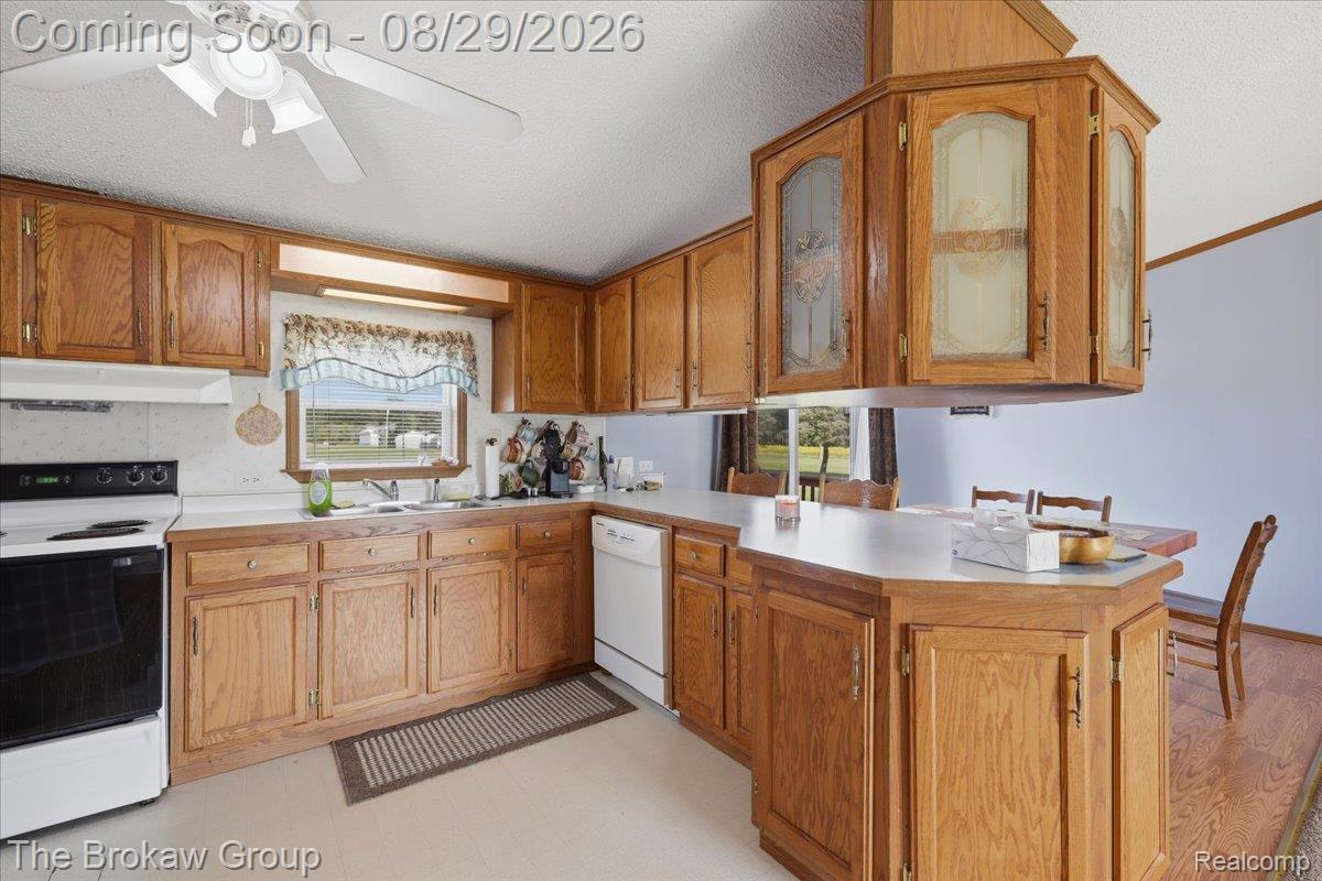 5189 North Webster Road Flushing, MI 48433 - Photo 18 of 46 Kitchen featuring wood cabinetry, white countertops, built-in dishwasher, white range, and ceiling fan
