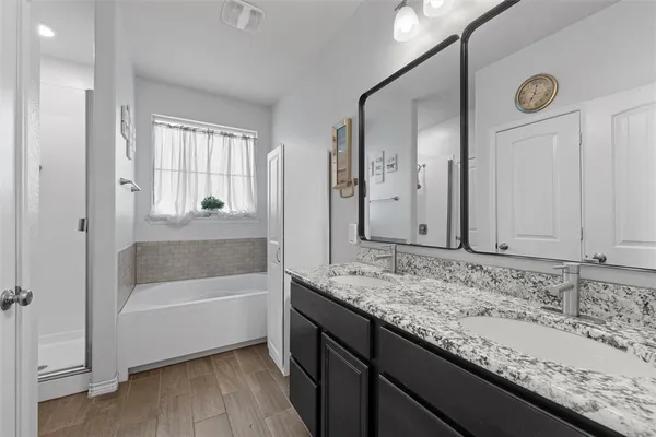 a bathroom with a granite countertop sink and mirror with bathtub